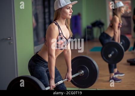 Donna Fitness preparazione alla pratica deadlift con pesi pesanti in palestra. Facendo femmina di peso pesante lavoro di sollevamento nel club salute. Foto Stock