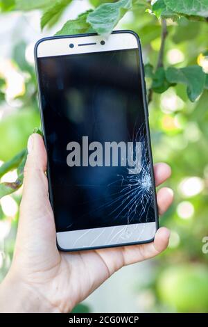 Vetro rotto dello smartphone. Messa a fuoco selettiva. La ragazza tiene in mano un telefono rotto accidentalmente. Si rompe sullo schermo dello smartphone. Foto Stock