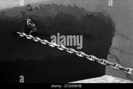 AJAXNETPHOTO. 1964. MONTEVIDEO, URUGUAY. - LA MORTE DEL MOLO - IL CORPO DI UN UOMO CHE GALLEGGIA NEL MOLO INTORNO ALLA CATENA DI ANCORAGGIO DI UNA NAVE DA CARICO.PHOTO:JONATHAN EASTLAND/AJAX REF:1964 115 Foto Stock