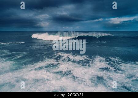 Condizioni meteorologiche Moody con forti onde che si infrangono lungo la costa Foto Stock