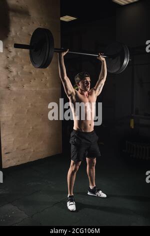 Muscular man at a crossfit gym lifting a barbell. Stock Photo
