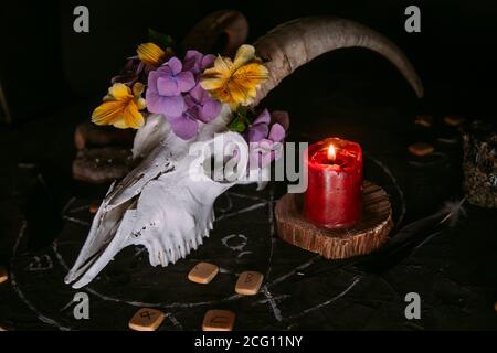 Gabbiano di capra bianco con corna, fiori, libro aperto vecchio, candele sul tavolo delle streghe. Concetto occulto, esoterico, divinazione e wicca. Halloween, giorno della dea Foto Stock