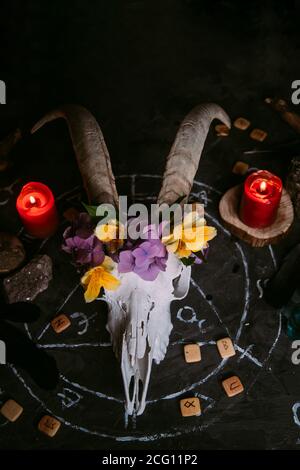 Gabbiano di capra bianco con corna, fiori, libro aperto vecchio, candele sul tavolo delle streghe. Concetto occulto, esoterico, divinazione e wicca. Halloween, giorno della dea Foto Stock