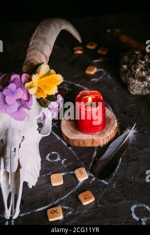 Gabbiano di capra bianco con corna, fiori, libro aperto vecchio, candele sul tavolo delle streghe. Concetto occulto, esoterico, divinazione e wicca. Halloween, giorno della dea Foto Stock