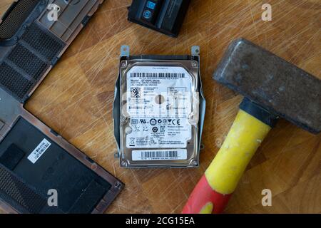 Un martello utilizzato per distruggere un disco rigido (HDD) martellandolo. Tema: Sicurezza dei dati dati dati personali, pulizia, eliminazione, tecnologia, rabbia, frustrazione Foto Stock