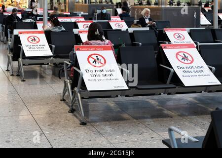 Posti a sedere bloccati con cartelli per mantenere la distanza sociale per la salute pubblica, terminal 3 dell'aeroporto di Heathrow, per la pandemia di Coronavirus Covid-19 Foto Stock