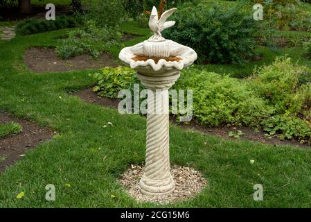 Unico e antico bagno ornamentale alto getto pietra ad uccello in cemento o bagno d'uccello e fontana d'acqua con porcione figurine come giardino decorazione Foto Stock