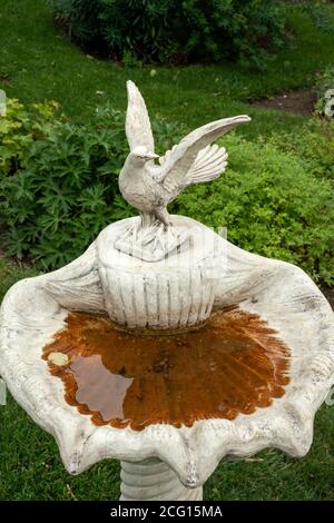 Unico e antico bagno ornamentale alto getto pietra ad uccello in cemento o bagno d'uccello e fontana d'acqua con porcione figurine come giardino decorazione Foto Stock