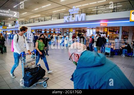 I viaggiatori che indossano maschere per il viso come precauzione contro la diffusione del covid 19.Schiphol aeroporto è occupato di nuovo in funzione di misure come KLM riceve un pacchetto di sostegno di 3.4 miliardi di euro per sopravvivere attraverso la crisi del coronavirus. Foto Stock