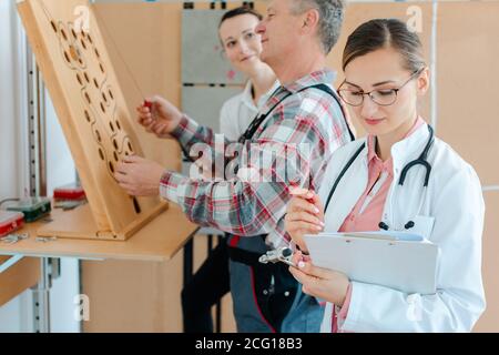 Il medico annoterà i risultati del test di destrezza della terapia occupazionale Foto Stock