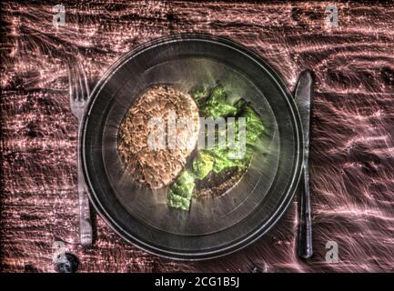 Un hamburger alla griglia con pomodori e insalata su un piatto. Foto Stock