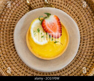 Le crostate di limone e fragola sono poste su una piastra bianca in un cestino di rattan. Foto Stock