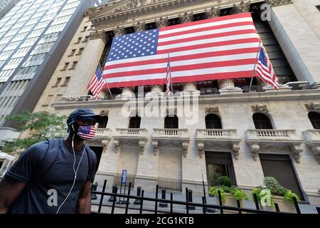 New York City, Stati Uniti. 8 settembre 2020. Un uomo che indossa una maschera a tema di bandiera americana cammina oltre una grande bandiera americana che copre la facciata della Borsa di New York a New York, NY, 8 settembre 2020. Le scorte si sono chiuse più in basso, in quanto il DOW è sceso di 630 punti a causa in parte dei timori di una rinascita del COVID-19 e dell'effetto economico che potrebbe avere sull'economia. (Anthony Behar/Sipa USA) Credit: Sipa USA/Alamy Live News Foto Stock
