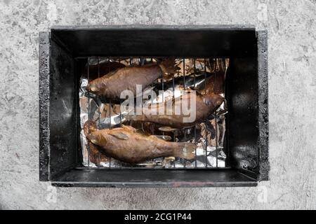 Crogiolo di pesce affumicato di fiume giace su una griglia di filo in una casa fumatore. Foto Stock