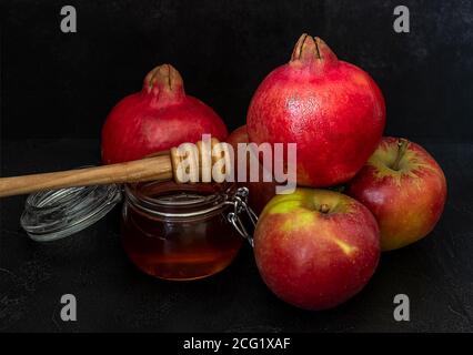 Miele, melograno e mele sulla tavola nera. Cartolina di Capodanno ebraico Rosh Hashanah. Foto Stock