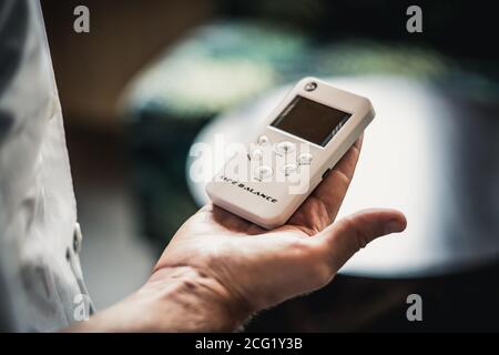 Le mani di giovane uomo tengono bio rezonans terapia alternativa medicina dispositivo, piccolo equilibrio di vita portatile bioresonanza per le malattie di trattamento dell'intestino Foto Stock