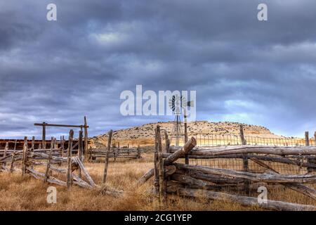 Un mulino a vento dietro un vecchio palo di legno recinto bestiame Corral nel sud-est dello Utah. Foto Stock