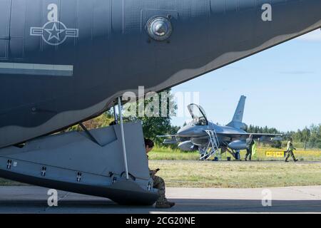 Un Airman con il 352d Special Operations Aircraft Maintenance Squadron siede sulla rampa posteriore di un MC-130J Commando II, con sede a RAF Mildenhall, Regno Unito, mentre un pilota della Royal Norwegian Air Force si prepara a lasciare il suo F-16 Fighting Falcon durante una missione di addestramento alla Rygge Air Station, Norvegia, 25 agosto 2020. L'integrazione con l'aeronautica norvegese ha permesso alla SOW 352 di rafforzare e rafforzare i legami con la nostra nazione partner e di garantire ulteriormente la regione strategica dell'alto nord. L'esercitazione ha fornito la formazione per i membri di 352d Special Operations Wing sulle capacità quali il ricov-ery del personale, per Foto Stock