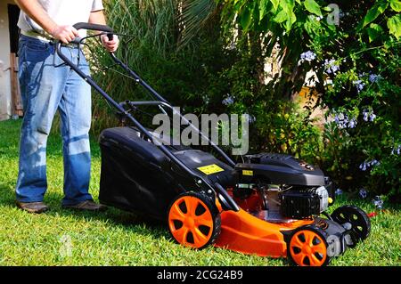 Uomo che utilizza un tosaerba a benzina a 4 tempi Voltor da 139 cc, Calahonda, Spagna. Foto Stock