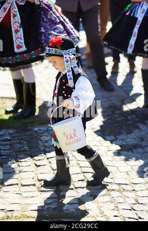 Ragazzo vestito in un costume tradizionale folk che porta un secchio nel villaggio di Holloko, paese ungherese Foto Stock