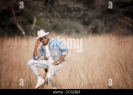 signore africano nel cespuglio africano che indossa un cappello e. occhiali da sole al sole Foto Stock