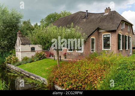 Giethoorn, Paesi Bassi - 28 agosto 2020: Casa con tetto di paglia su un piccolo canale Foto Stock