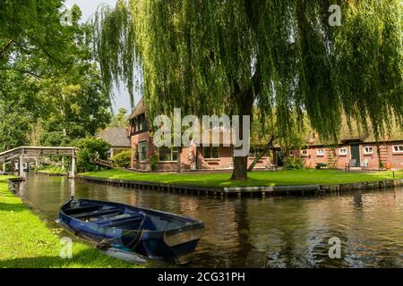 Giethoorn, Paesi Bassi - 28 agosto 2020: Salice piangente e barca di fronte ad una casa tradizionale olandese Foto Stock