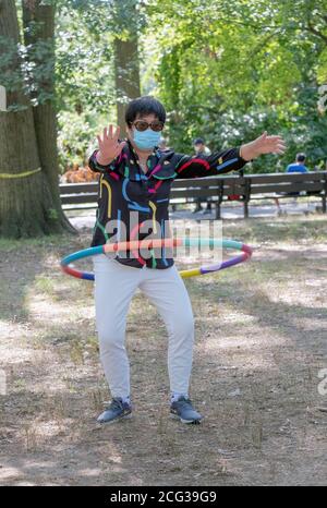 ALLUNGAMENTO ESTREMO. Un uomo si stende le spalle su una recinzione vicino al lago nel Kissena Park, Flushing, New York. Foto Stock