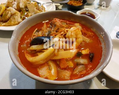 Jampong, zuppa cinese di noodle in stile coreano con brodo rosso e speziato a base di pesce aromatizzato con peperoncino in polvere. Calamari, cozze e maiale. Foto Stock