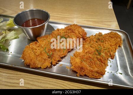 Tonkatsu, un piatto giapponese che consiste in una cotoletta di maiale impanata e fritta. Servito con salsa giapponese Worcestershire, riso e insalata di verdure. Foto Stock