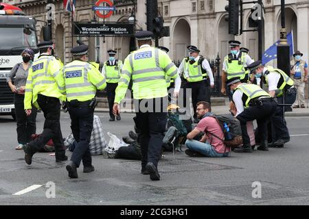 I poliziotti rimuovono i manifestanti che si sono seduti sulla strada dall'incrocio tra Parliament Street e Bridge Street da Parliament Square durante una protesta di Extinction Rebellion (XR) a Londra. Foto Stock