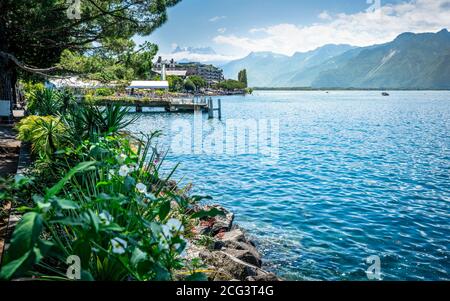 Montreux litorale con fiori e vista lago di Ginevra con le Alpi Montagne sullo sfondo durante la soleggiata giornata estiva a Montreux Vaud Svizzera Foto Stock