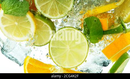 Fette di limone, arancio e lime che cadono sotto l'acqua isolate su sfondo bianco Foto Stock