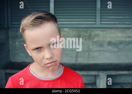 Carino ragazzo biondo europeo dagli occhi azzurri sembra triste e frustrato. Sta guardando con espressione pensiva di dolore nel suo volto di espressione face.emotive. Foto Stock