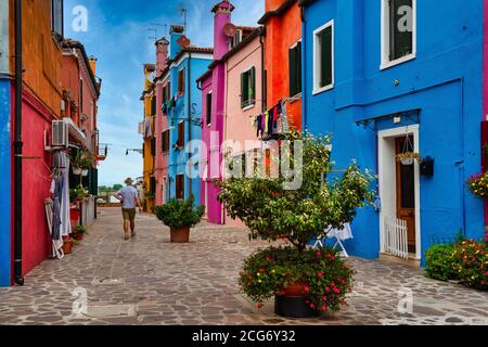 Uomo a piedi attraverso case multicolore, Burano, Venezia, Veneto, Italia Foto Stock