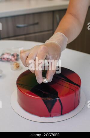 Donna che decora una torta di cioccolato di velluto rosso di cioccolato fatta in casa Foto Stock