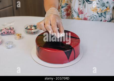 Donna che decora una torta di cioccolato di velluto rosso di cioccolato fatta in casa Foto Stock