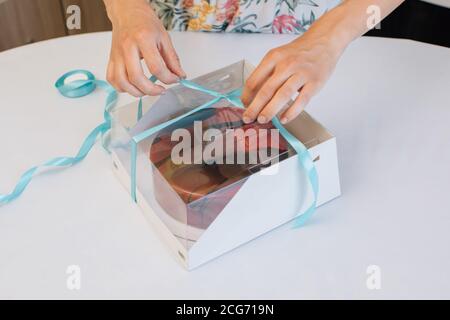 Donna che impacchettano la torta fatta in casa in una scatola del regalo Foto Stock