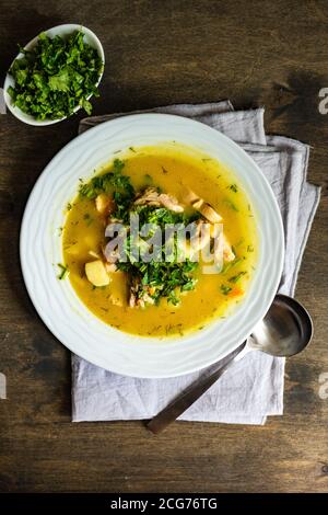 Ciotola di zuppa di pollo e coriandolo su un tavolo di legno Foto Stock