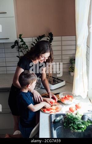 Bella mamma e figlio tagliato verdure fresche per insalata con un coltello Foto Stock