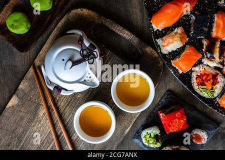 Piatti di sushi maki assortiti e sushi nigiri un tavolo con tè verde Foto Stock