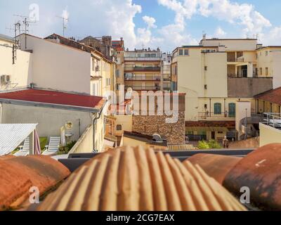 Vista dal tetto in tegole rosse sul cortile chiuso e accogliente circondato da un edificio scolastico e vecchie case tradizionali in sabbia colore con terrazze e balconi Foto Stock