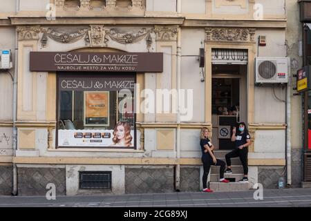 BELGRADO, SERBIA - 28 LUGLIO 2020: Due donne, dipendenti e lavoratori di un salone di bellezza, in piedi di fronte alla boutique con un viso respiratorio ma Foto Stock