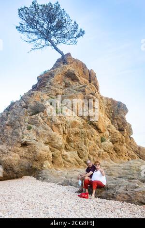 Coppia in pensione seduta su una zona rocciosa vicino al mare Foto Stock