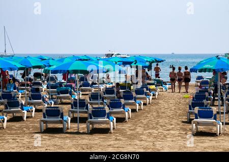 Fila su fila di lettini e ombrelloni in una calda giornata estiva sulla spiaggia di Larnaca, Cipro. Foto Stock