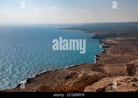 Guardando ad ovest sulla costa arida e rocciosa e il mare da Capo Greco, nel sud-est di Cipro. Foto Stock