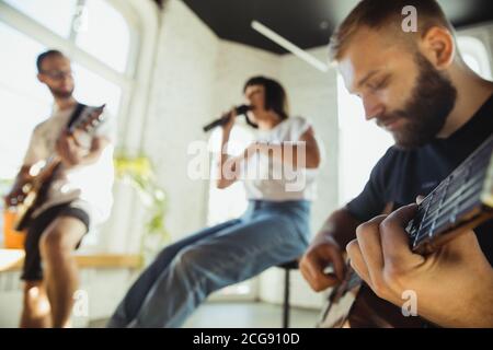 Ritmo. Band musicista jamming insieme in un posto di lavoro d'arte con strumenti. Uomini e donne caucasici, musicisti, suonando e cantando insieme. Concetto di musica, hobby, emozioni, occupazione artistica. Foto Stock