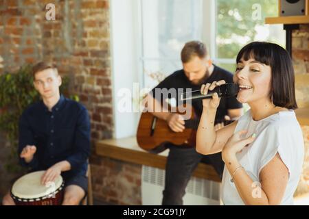 Ritmo. Band musicista jamming insieme in un posto di lavoro d'arte con strumenti. Uomini e donne caucasici, musicisti, suonando e cantando insieme. Concetto di musica, hobby, emozioni, occupazione artistica. Foto Stock