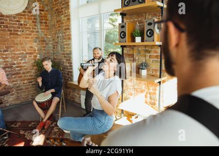 Ritmo. Band musicista jamming insieme in un posto di lavoro d'arte con strumenti. Uomini e donne caucasici, musicisti, suonando e cantando insieme. Concetto di musica, hobby, emozioni, occupazione artistica. Foto Stock