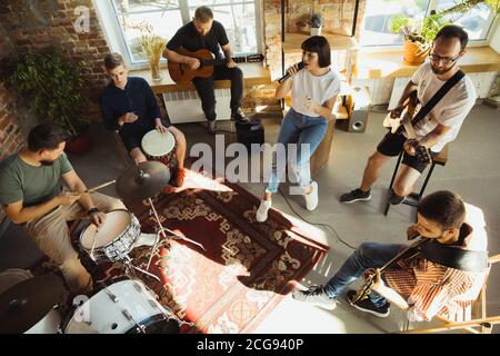 Ritmo. Band musicista jamming insieme in un posto di lavoro d'arte con strumenti. Uomini e donne caucasici, musicisti, suonando e cantando insieme. Concetto di musica, hobby, emozioni, occupazione artistica. Foto Stock